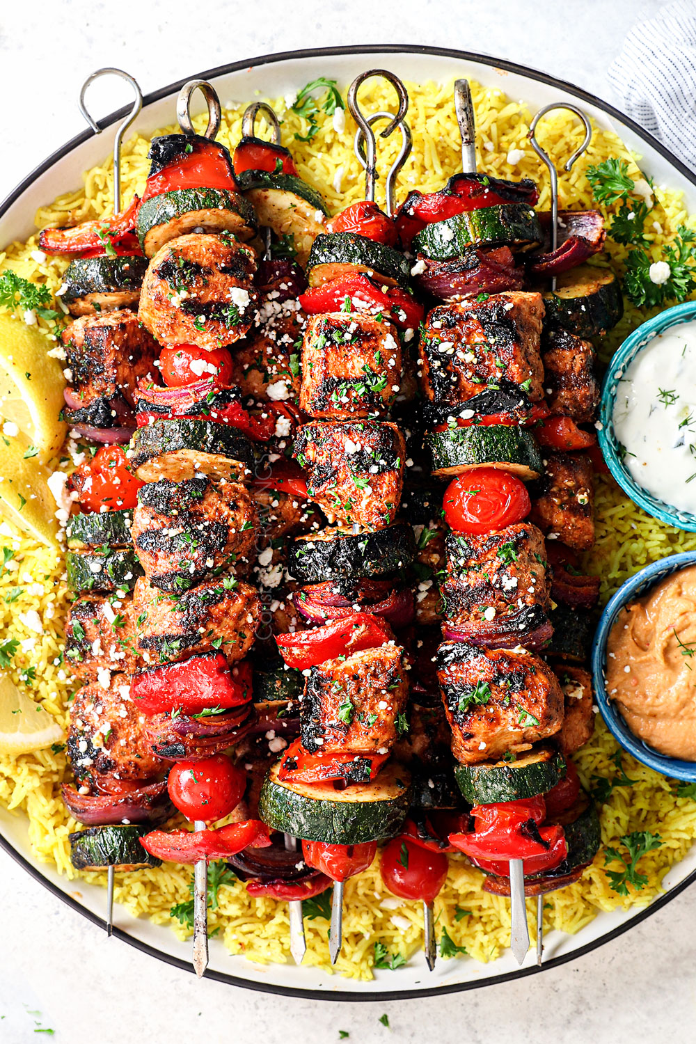 Greek chicken kabobs lined a plate with Greek lemon rice