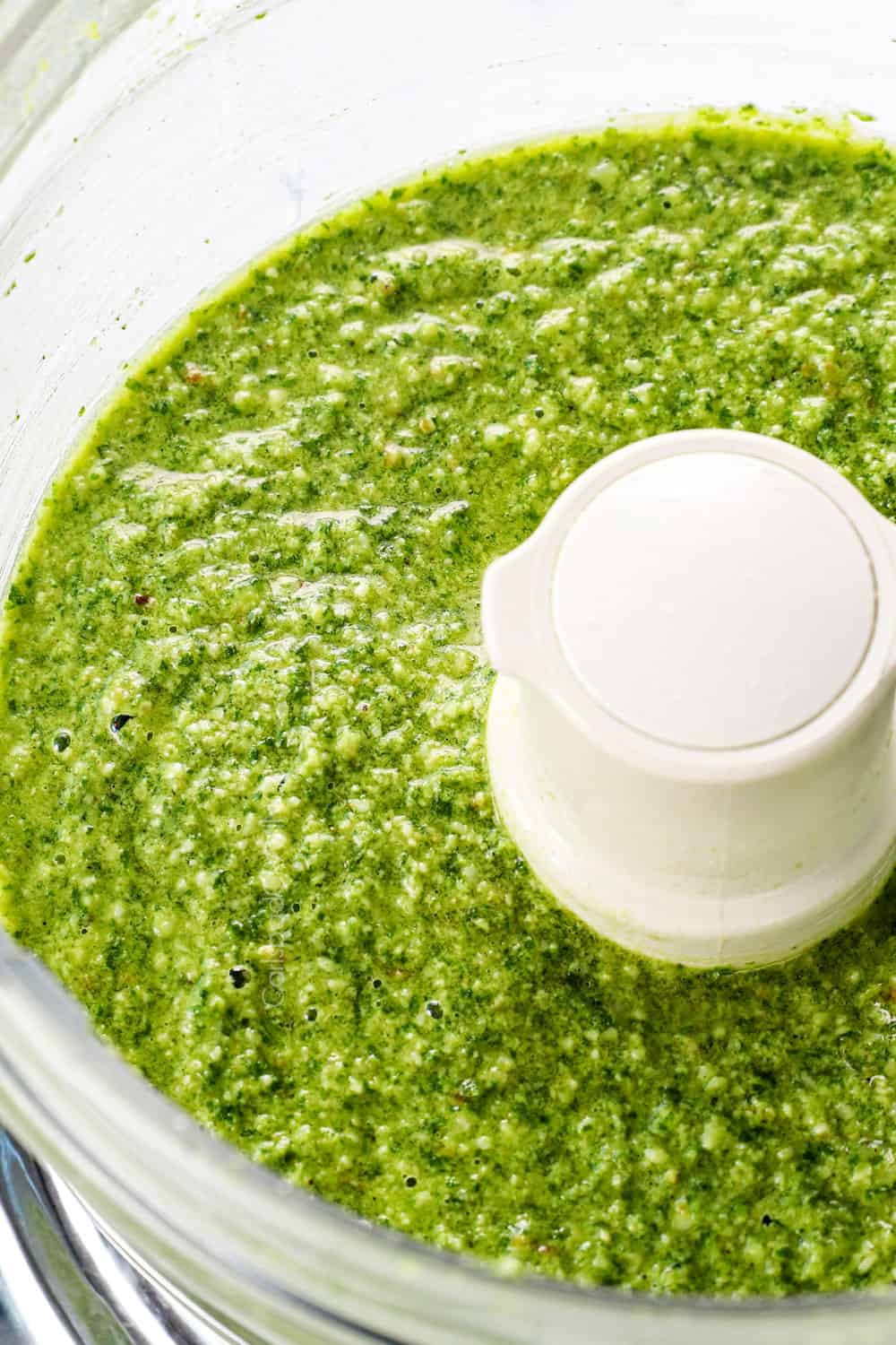 showing how to make pesto by pulsing Parmesan, basil, garlic and olive oil until smooth