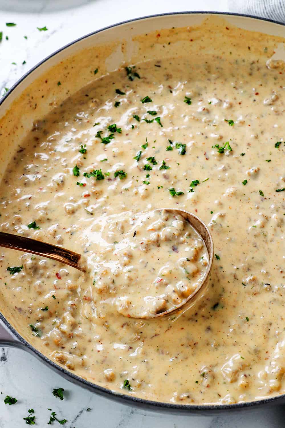 a ladle of sausage gravy for biscuits and gravy showing how creamy it is