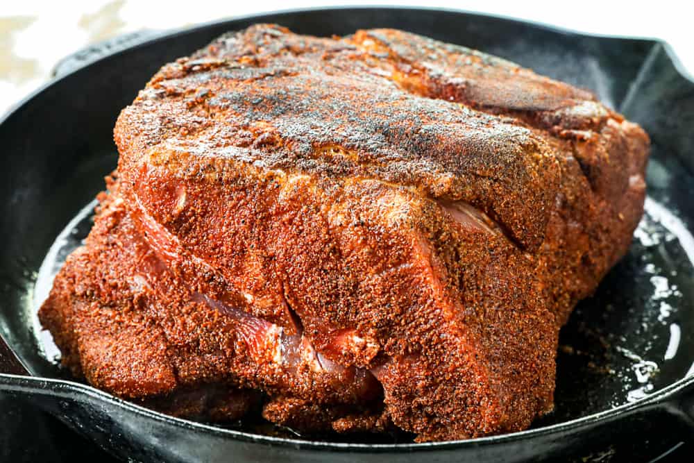 showing how to make BBQ pulled pork by searing pork butt in a cast iron skillet