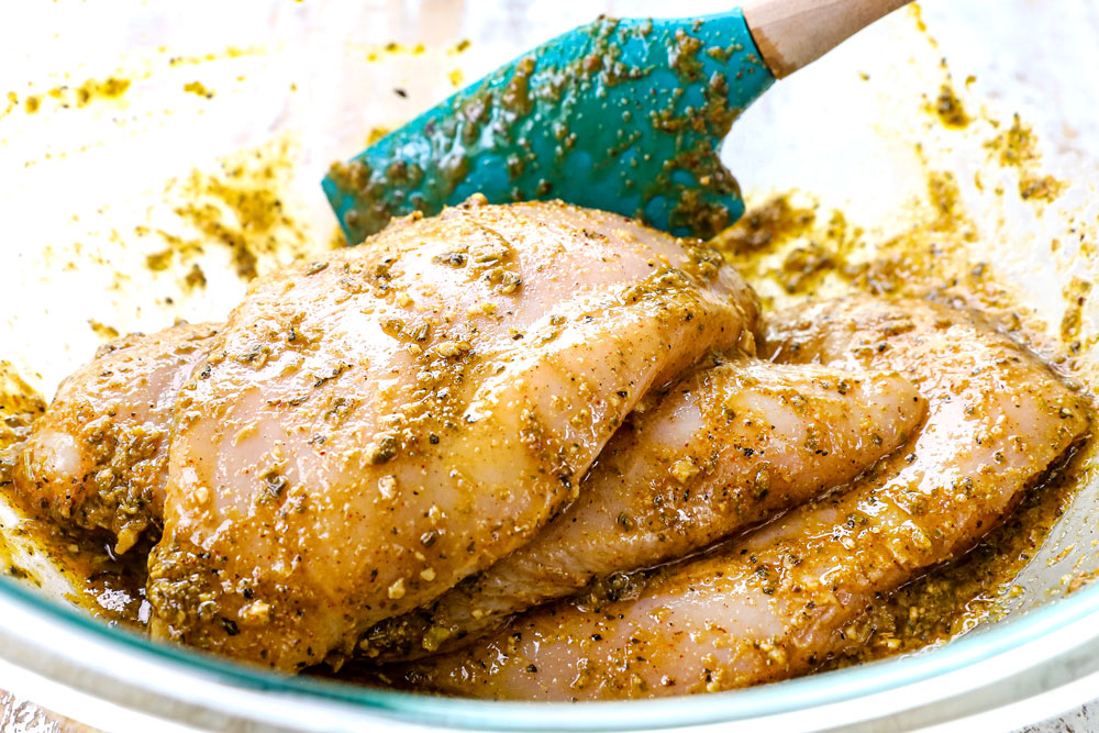 showing how to make Italian Chicken marinade by combining chicken with olive oil, pesto, red wine vinegar, lemon juice, garlic and Italian seasonings