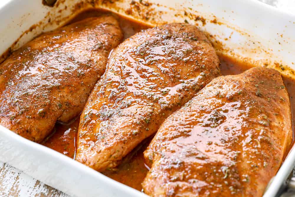 showing how to make jerk chicken tacos by marinating chicken with jerk seasoning