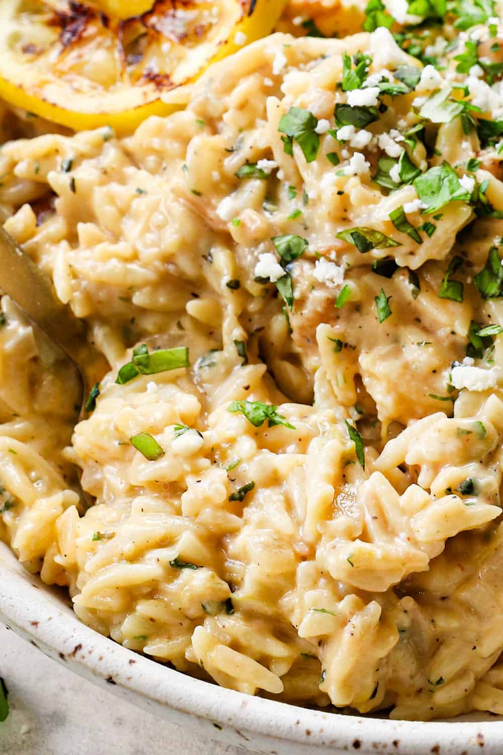 a fork taking a bite of lemon chicken orzo showing how creamy it is