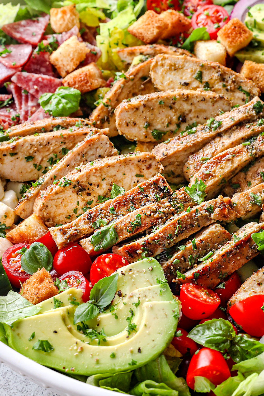 serving Mediterranean chicken salad recipe in a bowl garnished by parsley