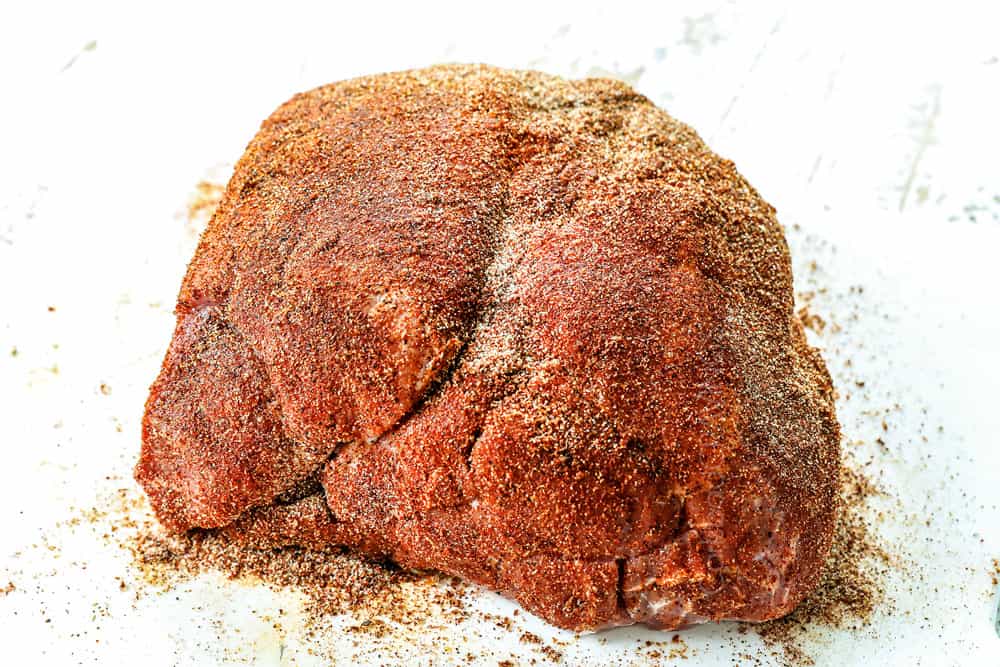 showing how to make pulled pork sandwiches by rubbing spices all over the pork