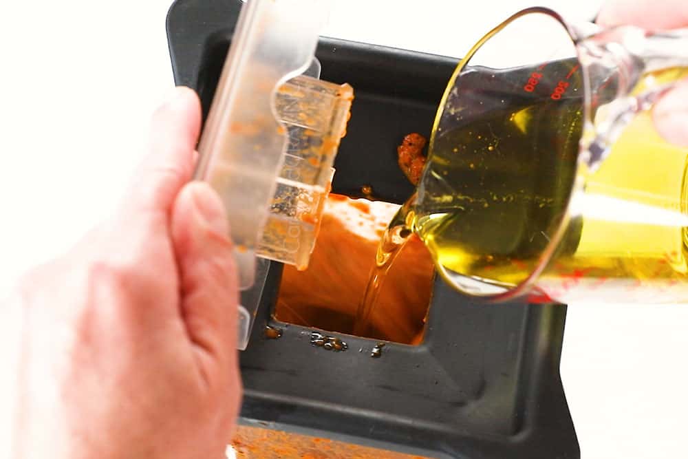 showing how to make peri peri chicken by making peri peri sauce by streaming the olive oil into the blender