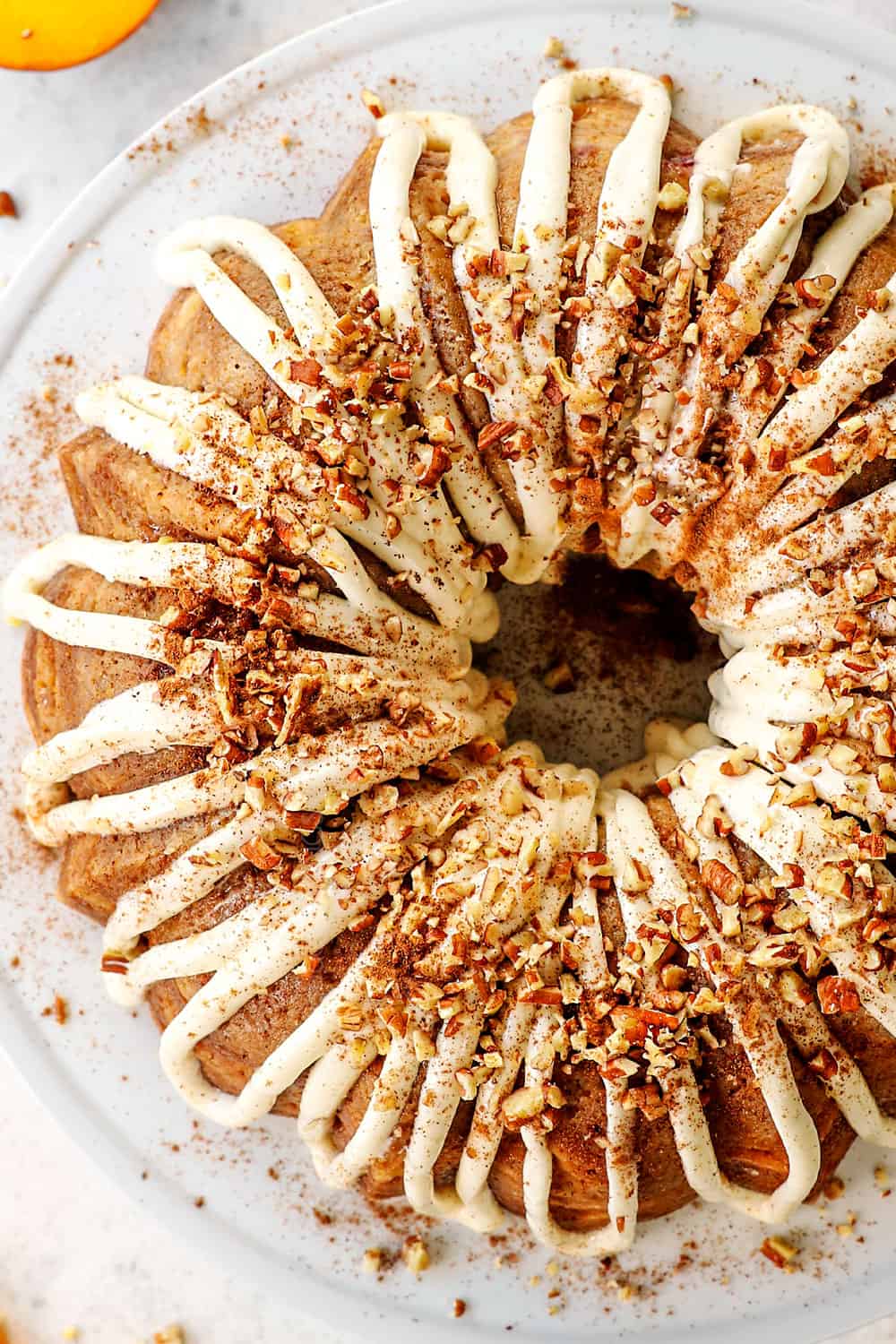 top view of peach cake recipe drizzled with frosting and garnished with nuts