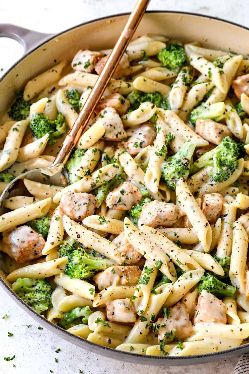 Chicken and broccoli Alfredo with penne in a pan garnished with Parmesan cheese
