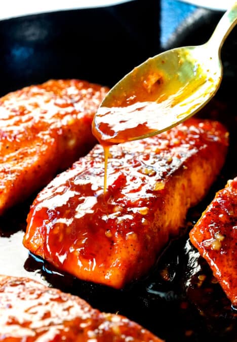 showing how to make firecracker salmon by pouring the sauce over top the pan seared salmon