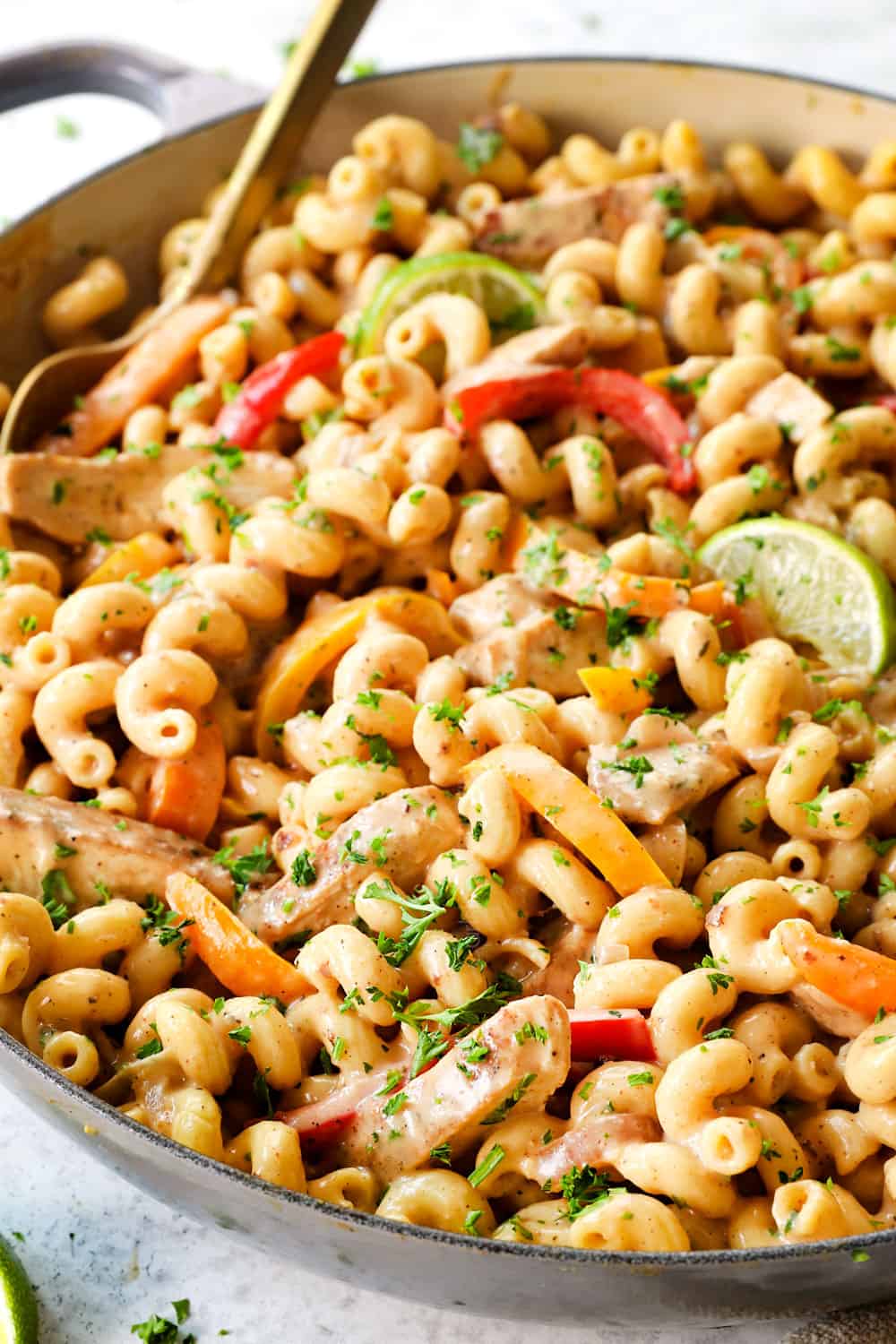 showing how to make jerk chicken pasta (Rasta pasta) by tossing chicken with pasta in a creamy sauce