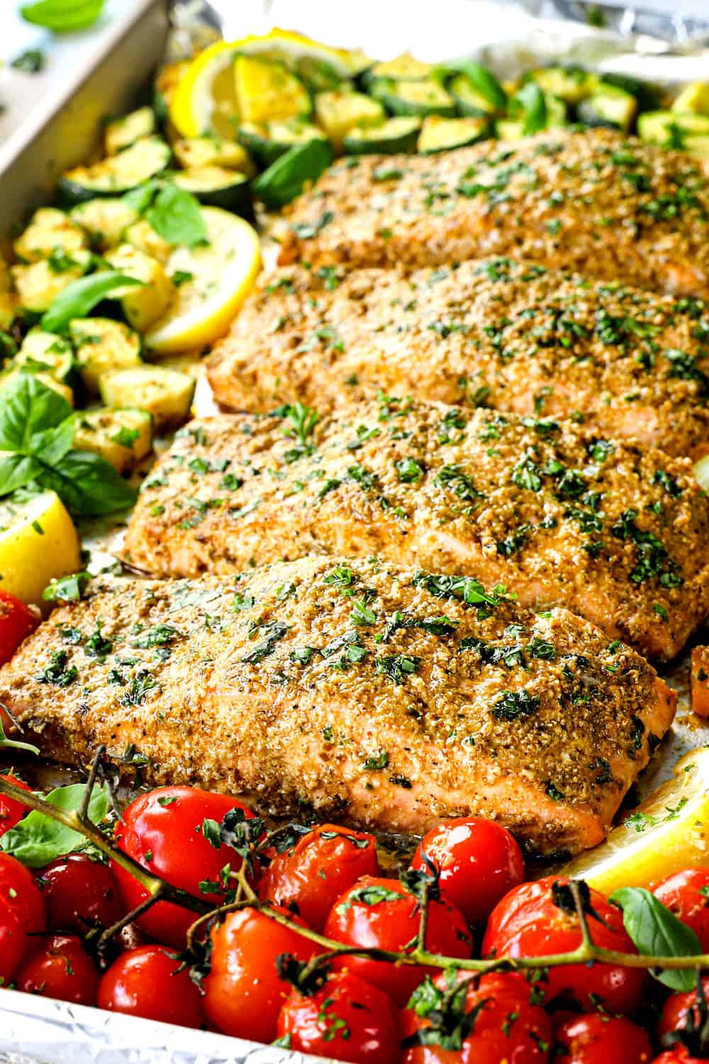 showing how to make pesto salmon by lining salmon fillets on a baking sheet and topping with pesto