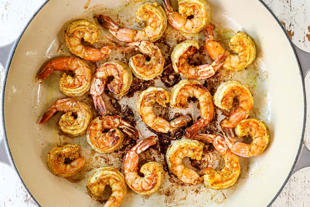 showing how to make coconut shrimp curry recipe by sautรฉing shrimp in a pan with oil