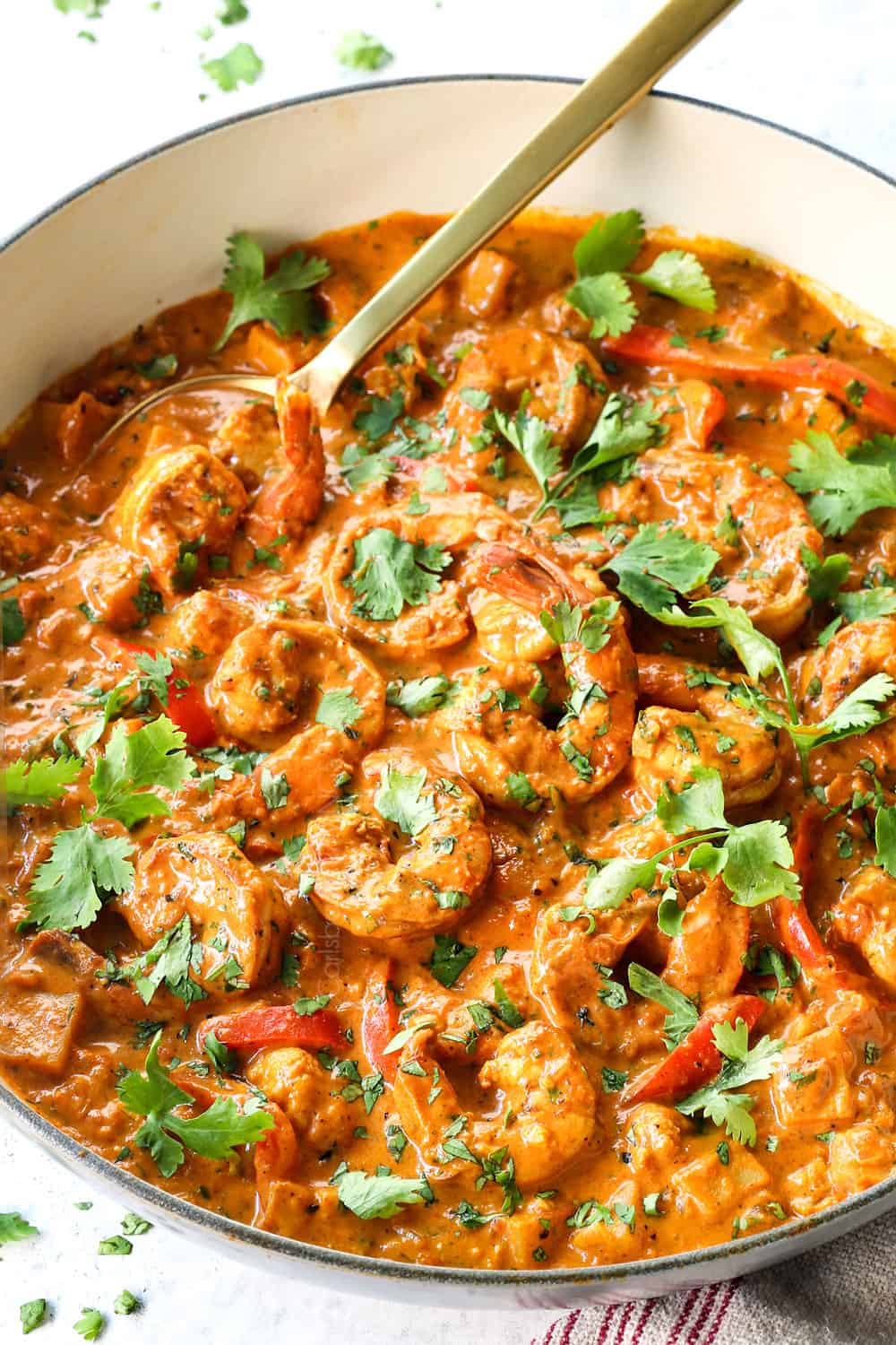 showing how to make coconut curry shrimp by simmering shrimp with coconut milk, crushed tomatoes and Indian spices
