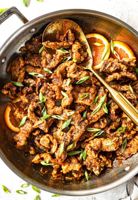 top view of making orange beef by garnishing with green onions and sesame seeds