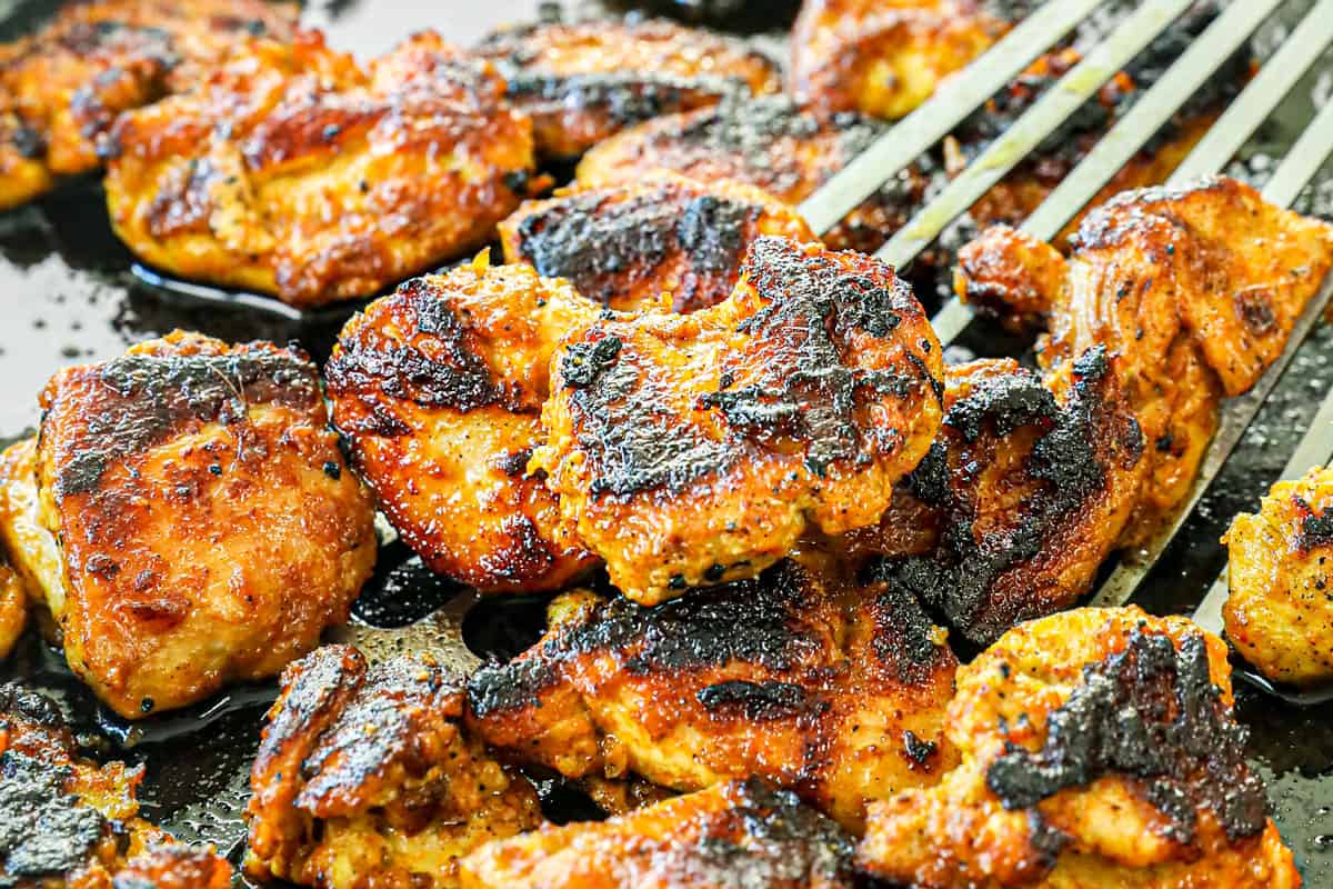 showing how to make Chicken Tikka Masala recipe by searing the chicken in a cast iron skillet until charred