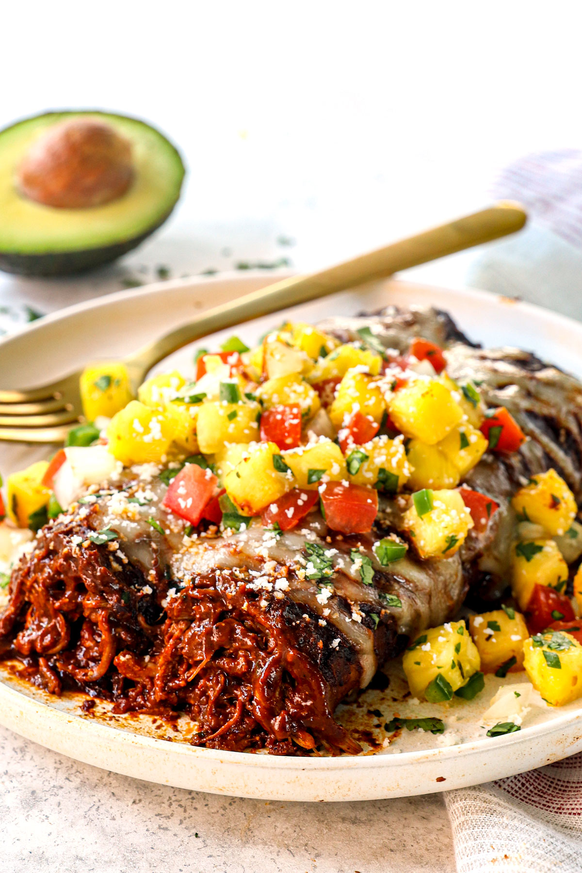 up close of serving chicken mole enchiladas on a plate with salsa and cotija cheese