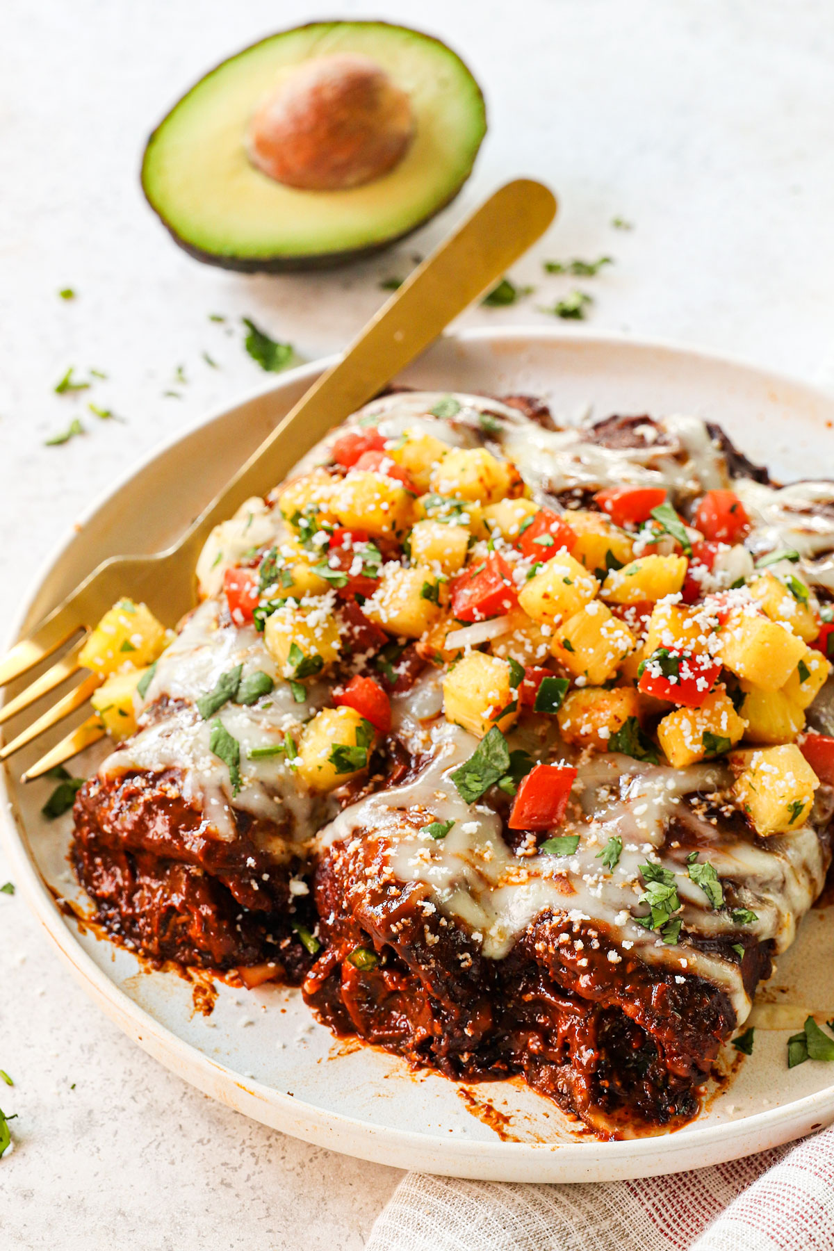serving chicken mole enchiladas on a plate garnished by salsa and cotija cheese