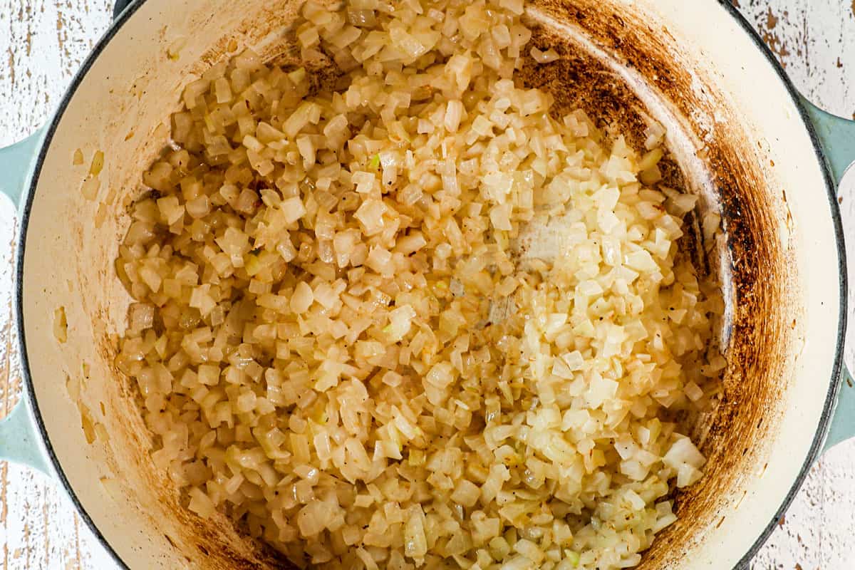showing how to make mole sauce (Mole Poblano) by sautรฉing garlic and onions in a Dutch oven