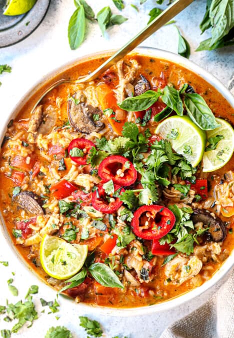 top view of coconut curry soup with chicken in a bowl with cilantro and limes