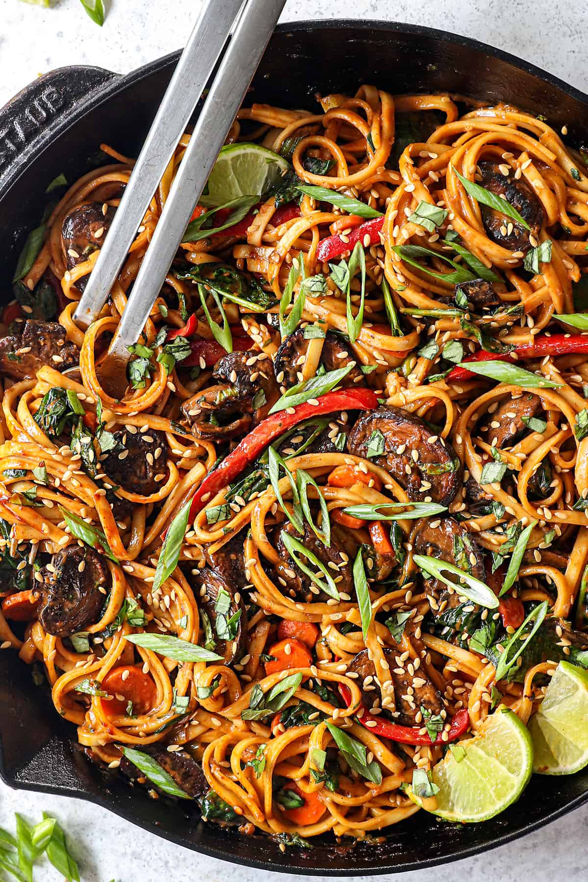 top view showing how to make udon noodles by garnishing with green onions and sesame seeds in the skillet
