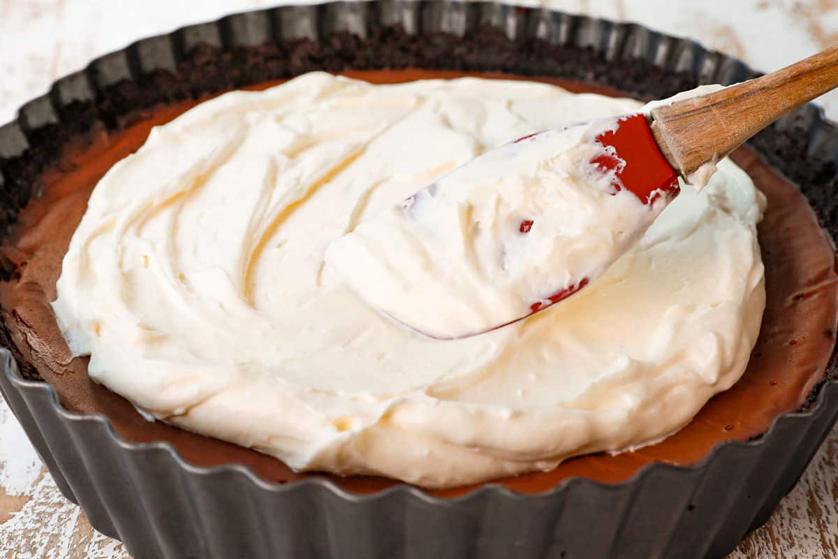showing how to make Chocolate Cream Pie recipe by spreading whipped cream over the chocolate custard