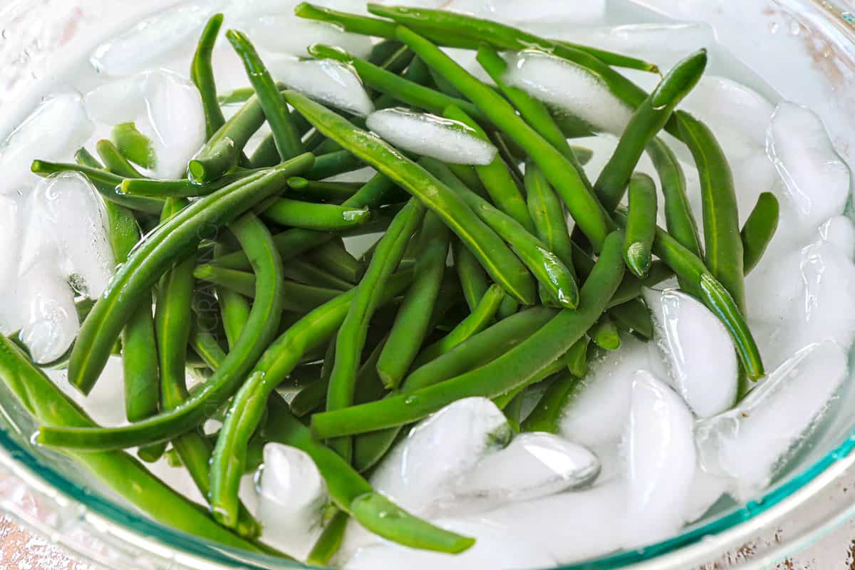 showing how to make Green Beans Almondine by blanching the green beans in a bowl of ice water