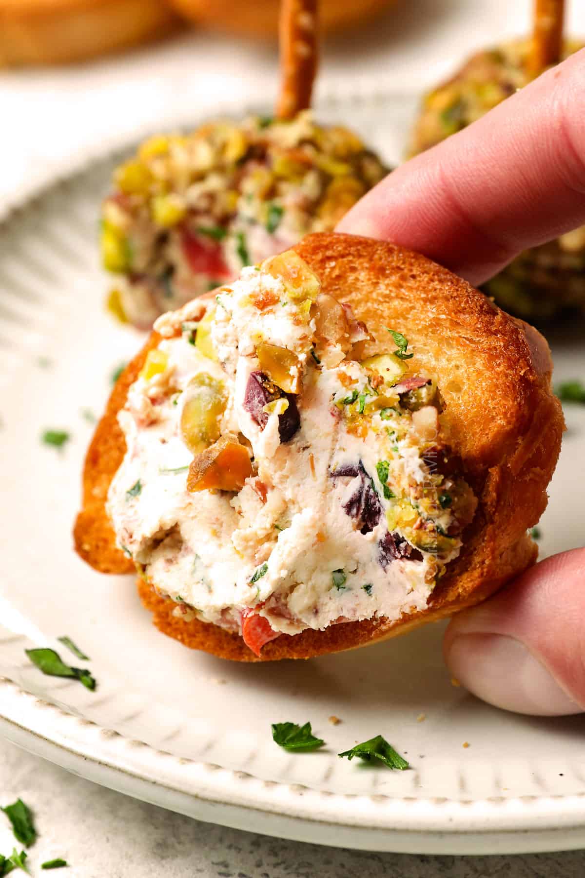 showing how to serve mini cheese balls by spreading onto a crostini