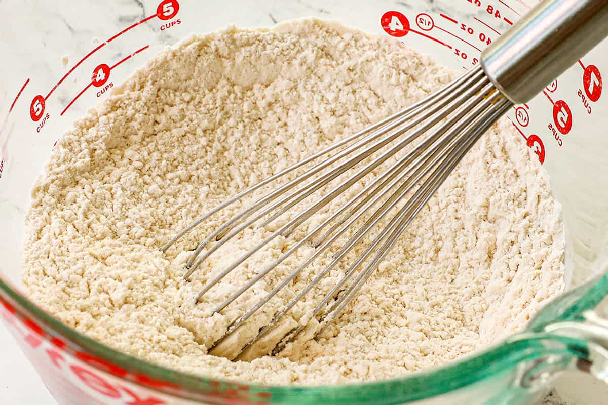 showing how to make pecan pie cookies by whisking the flour, baking soda and baking powder together in a bowl