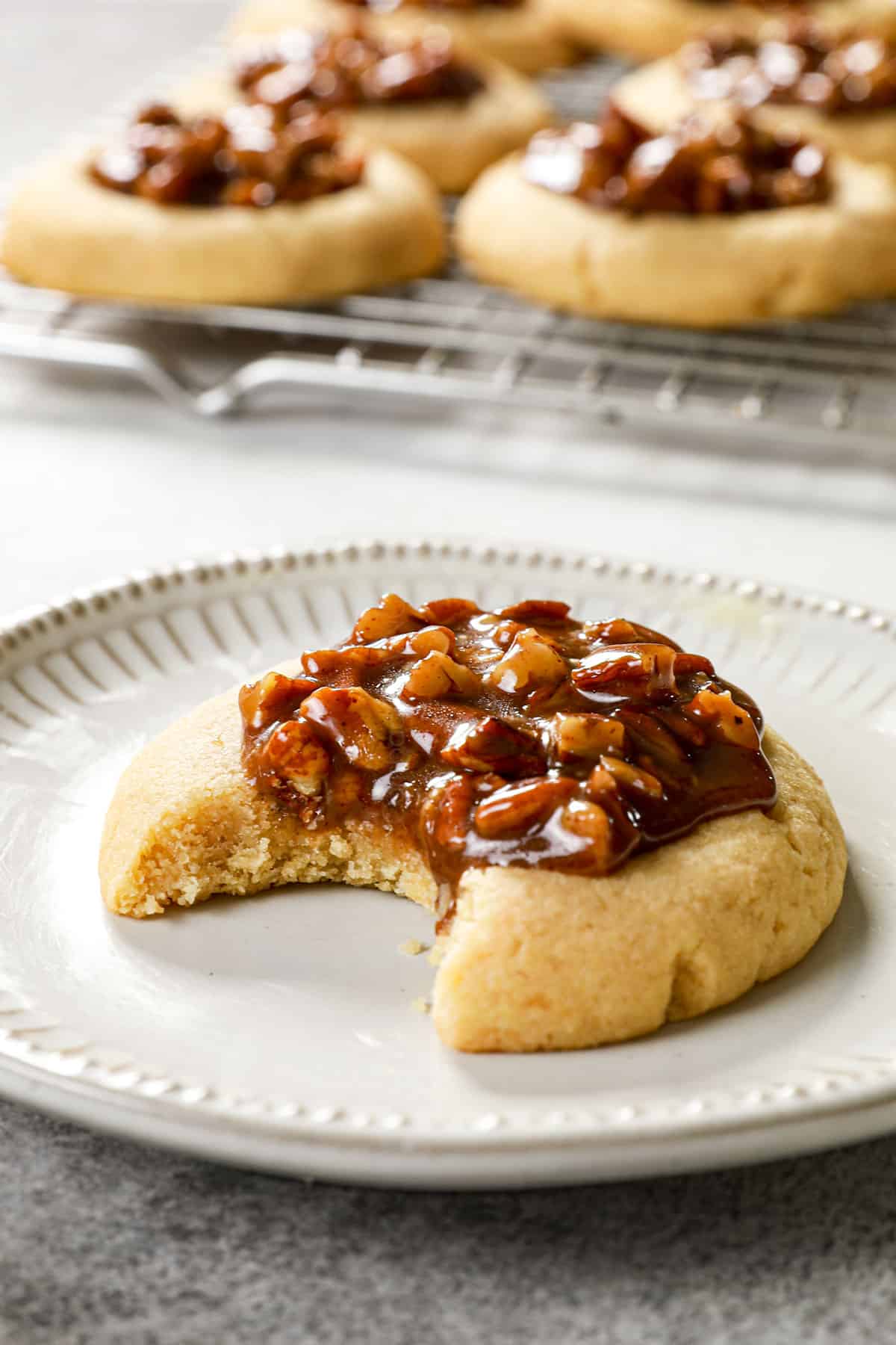 up close of a pecan pie thumbprint cookie with a bite taken out showing the gooey filling