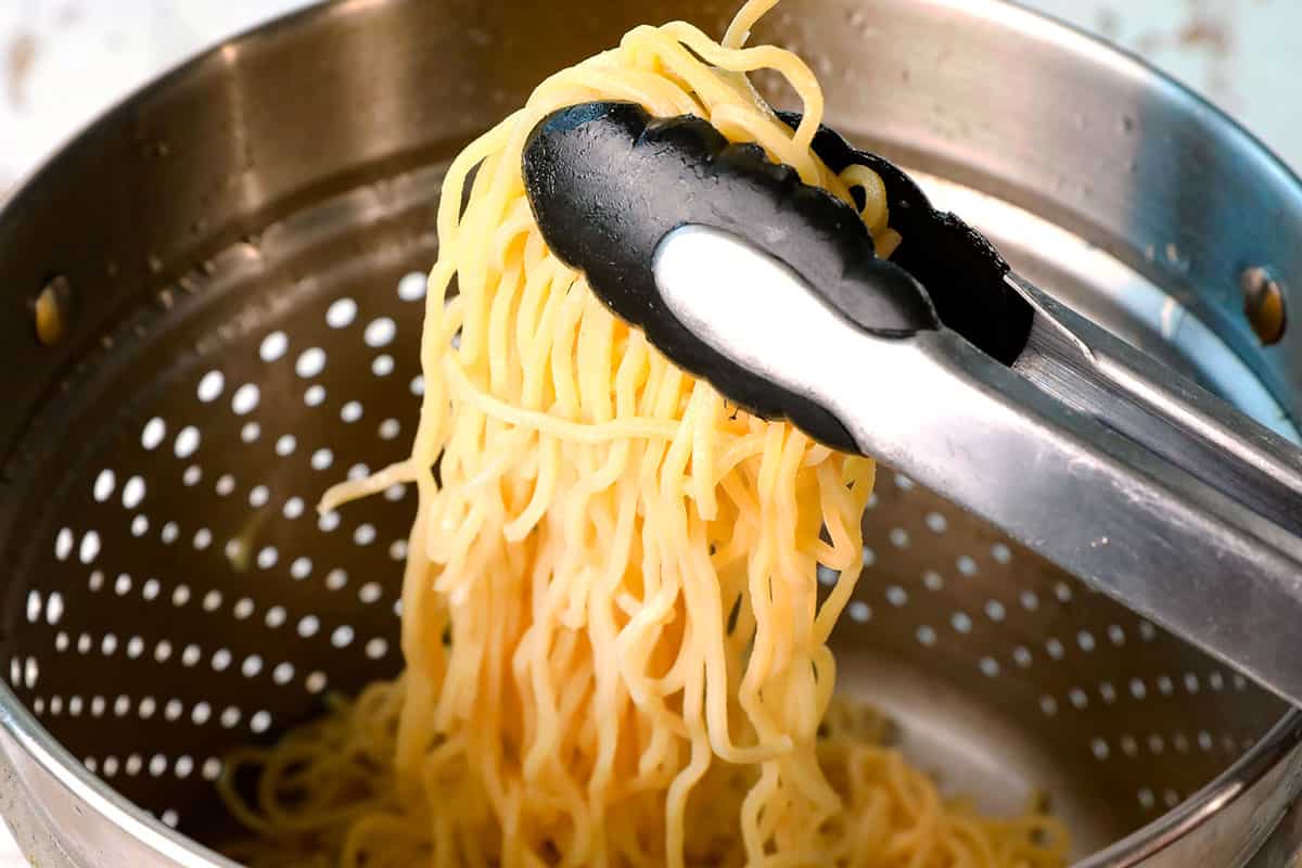 showing how to make Asian meatballs by tossing noodles in sesame oil