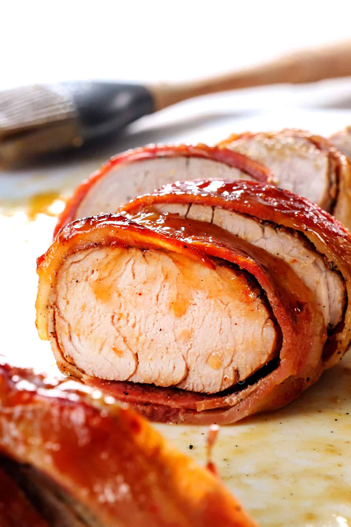 showing how to make bacon wrapped pork tenderloin by slicing pork