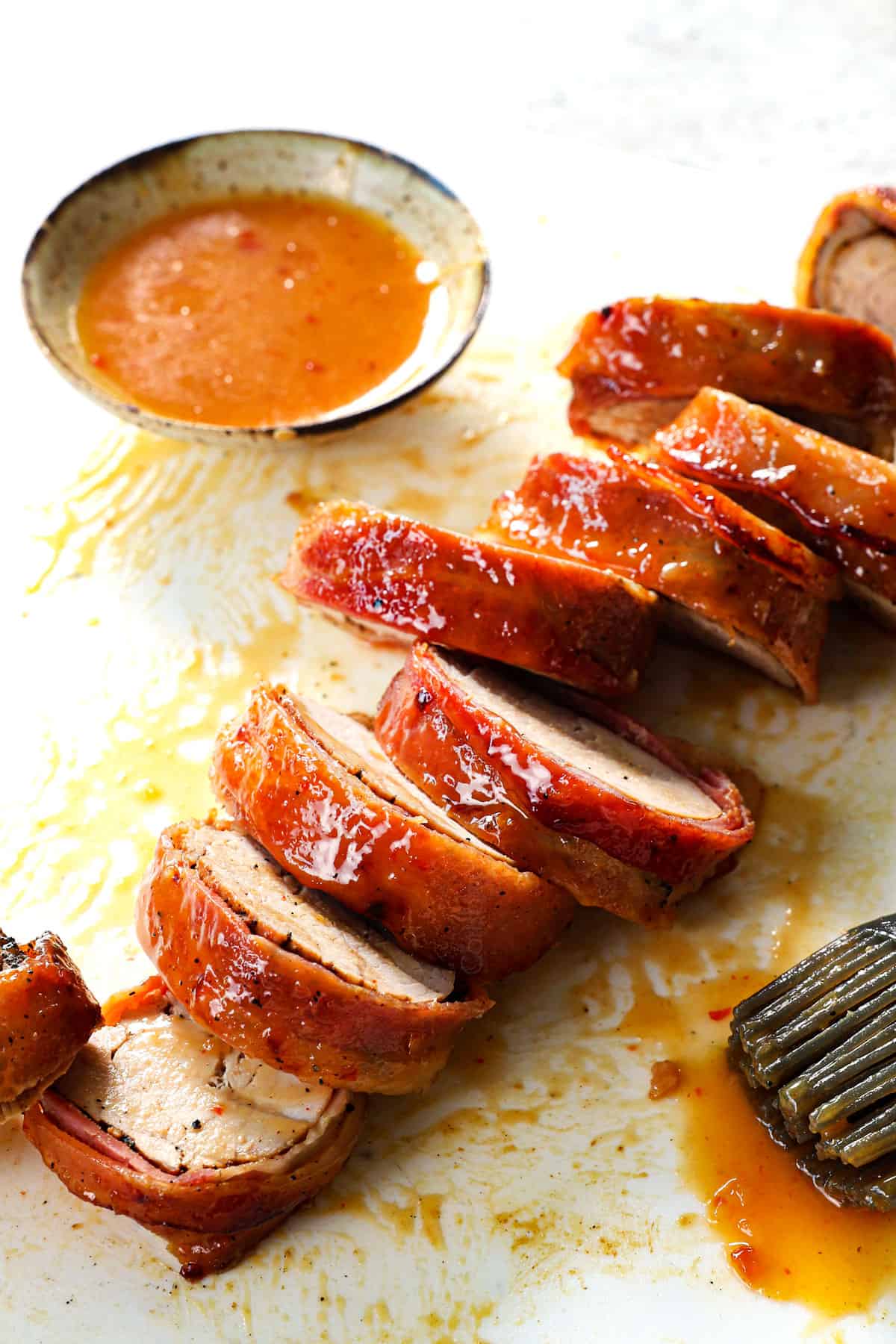 showing how to make bacon wrapped pork tenderloin by slicing pork into slices