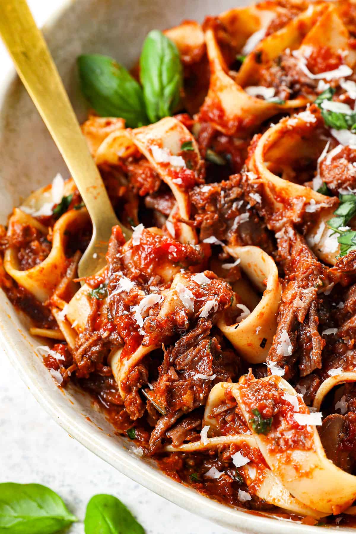 up close of twirling beef ragu recipe on a fork showing the saucy ragu sauce