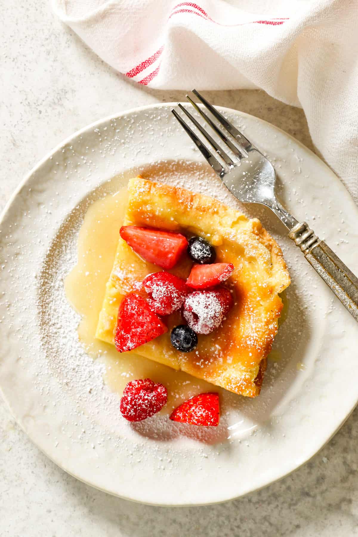 top view of a slice of German pancake on a white plate with berries