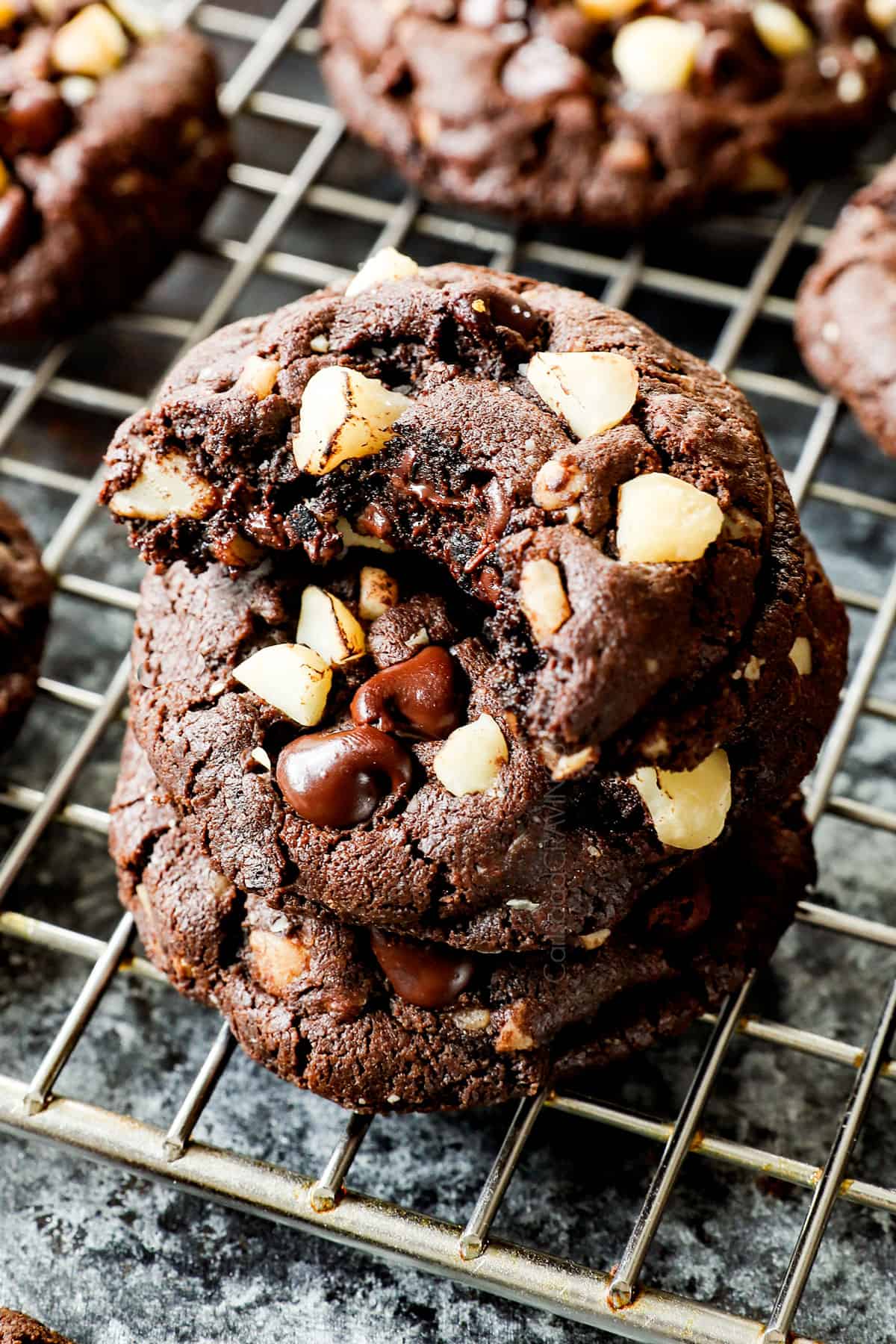 macadamia nut cookies with a bite taken out of a cookie showing the macadamia nuts and melted chocolate inside