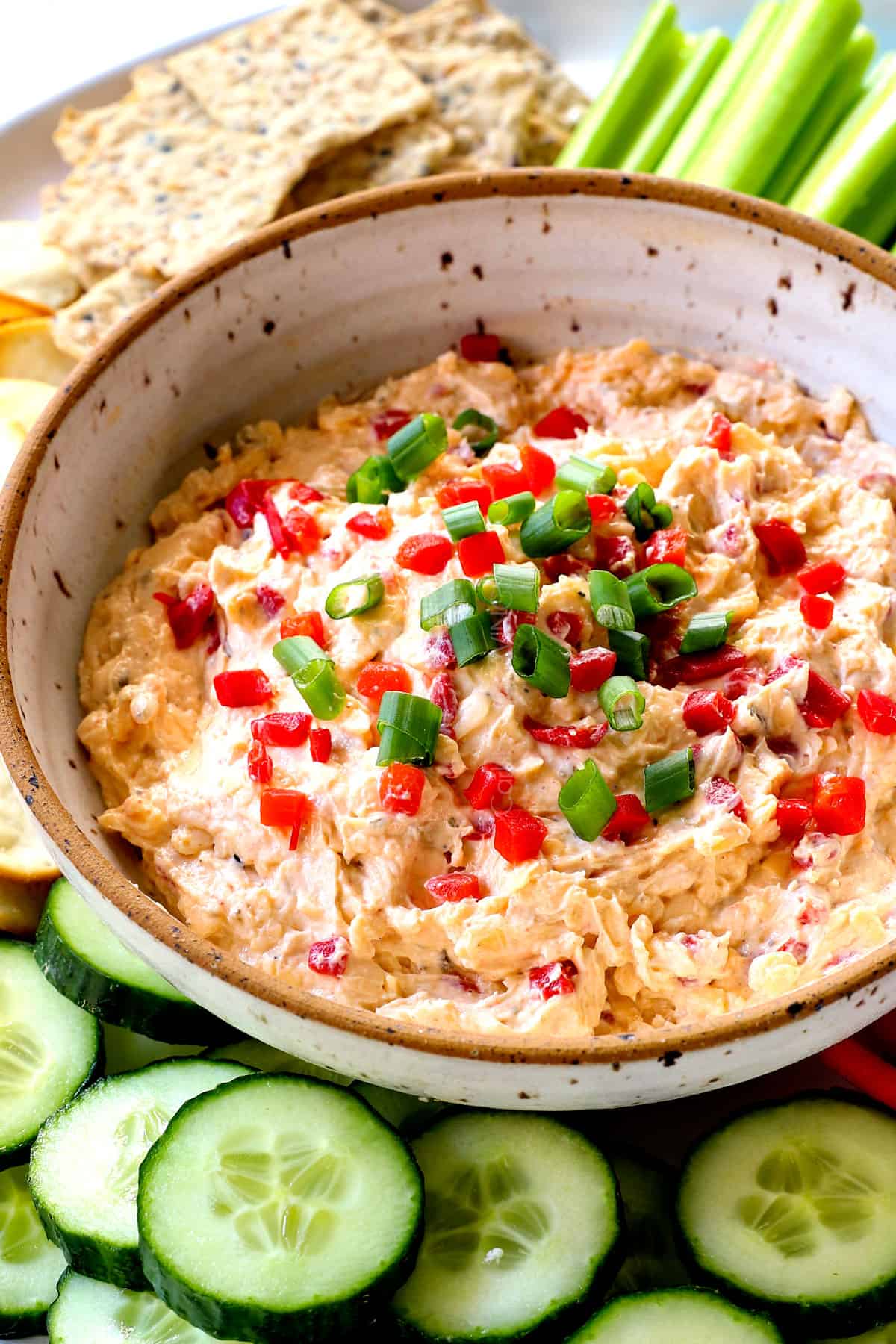 showing how to serve pimento cheese recipe adding to a platter with cucumbers, celery, bell peppers, cauliflower and crackers
