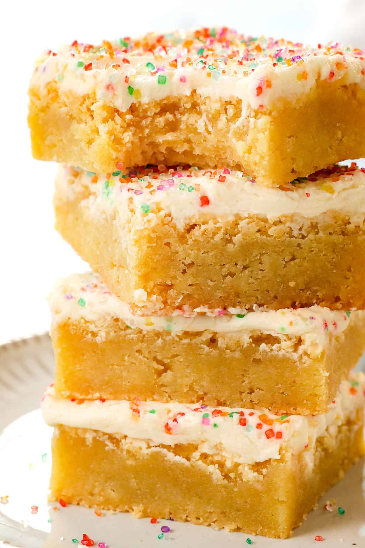 a stack of sugar cookie bars with cream cheese frosting decorated with sprinkles