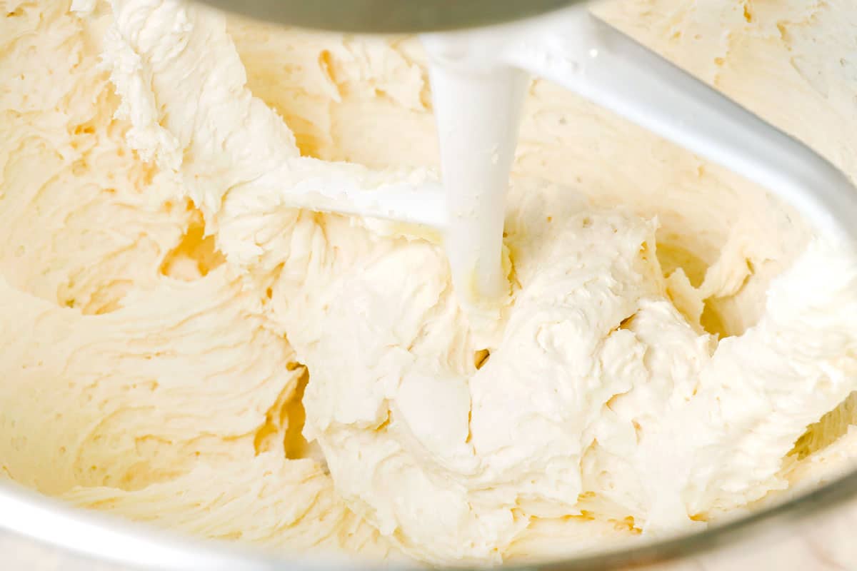 showing how to make sugar cookie bars by beating butter, cream cheese and sugar together until smooth and fluffy