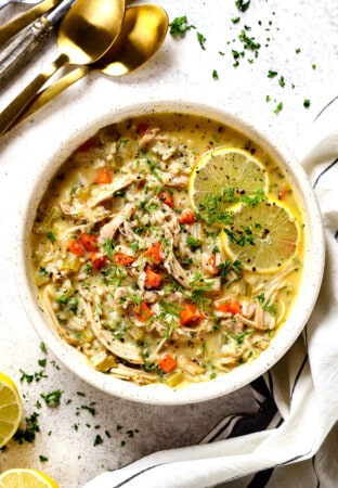 top view of a serving a bowl of traditional Avgolemono Soup (Greek Lemon Chicken Soup) garnished with lemon slices