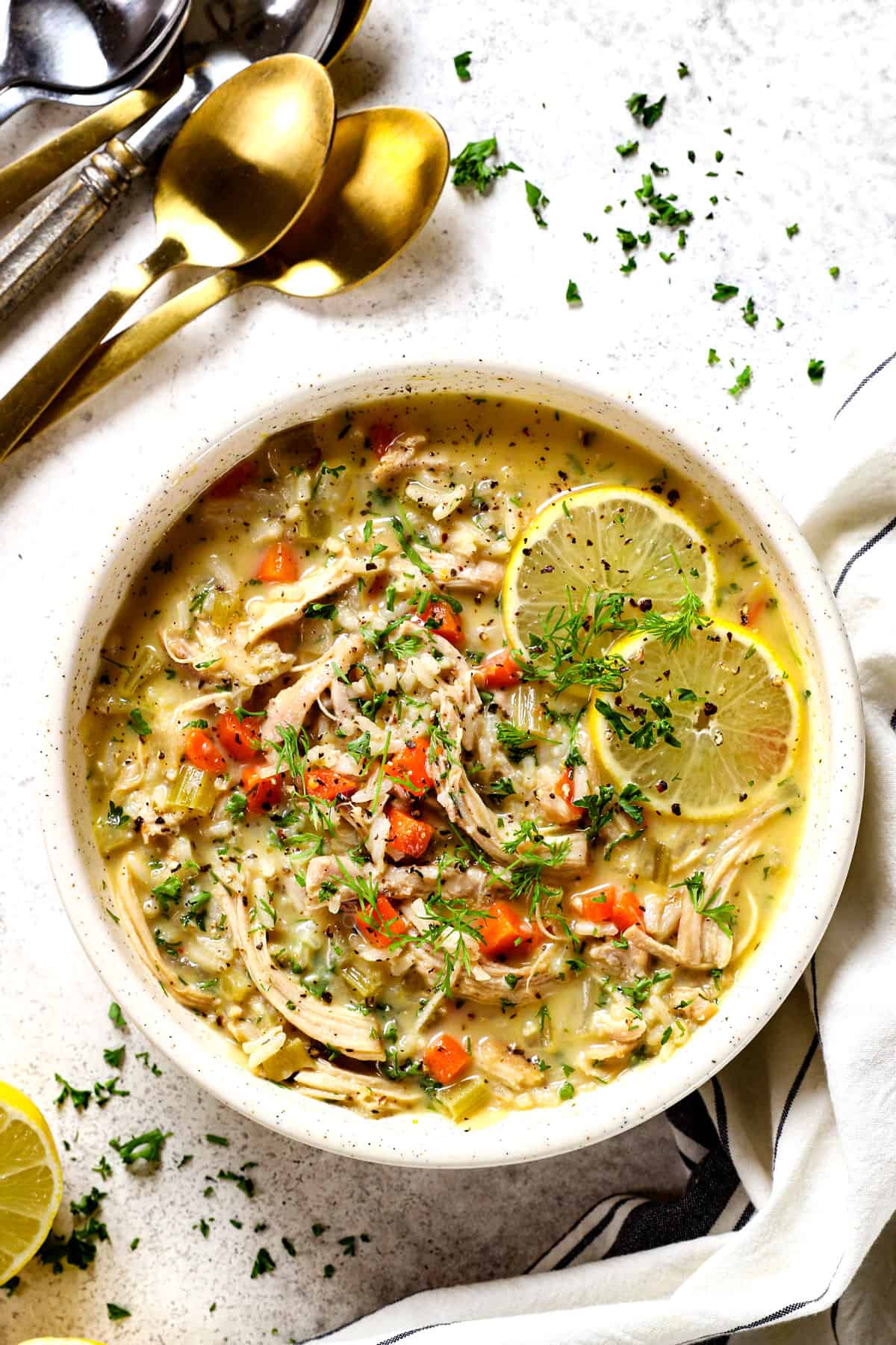top view of a serving a bowl of traditional Avgolemono Soup (Greek Lemon Chicken Soup) garnished with lemon slices