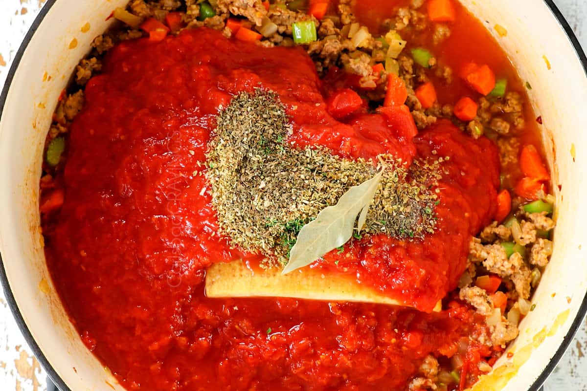 showing how to make pasta fagioli recipe (pasta fazool) by adding crushed tomatoes, Italian seasonings and Parmesan rind to the soup