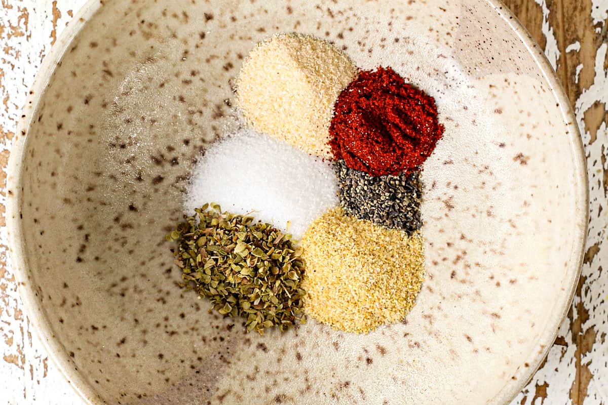 showing how to make shredded chicken recipe by adding the spices to a bowl and mixing