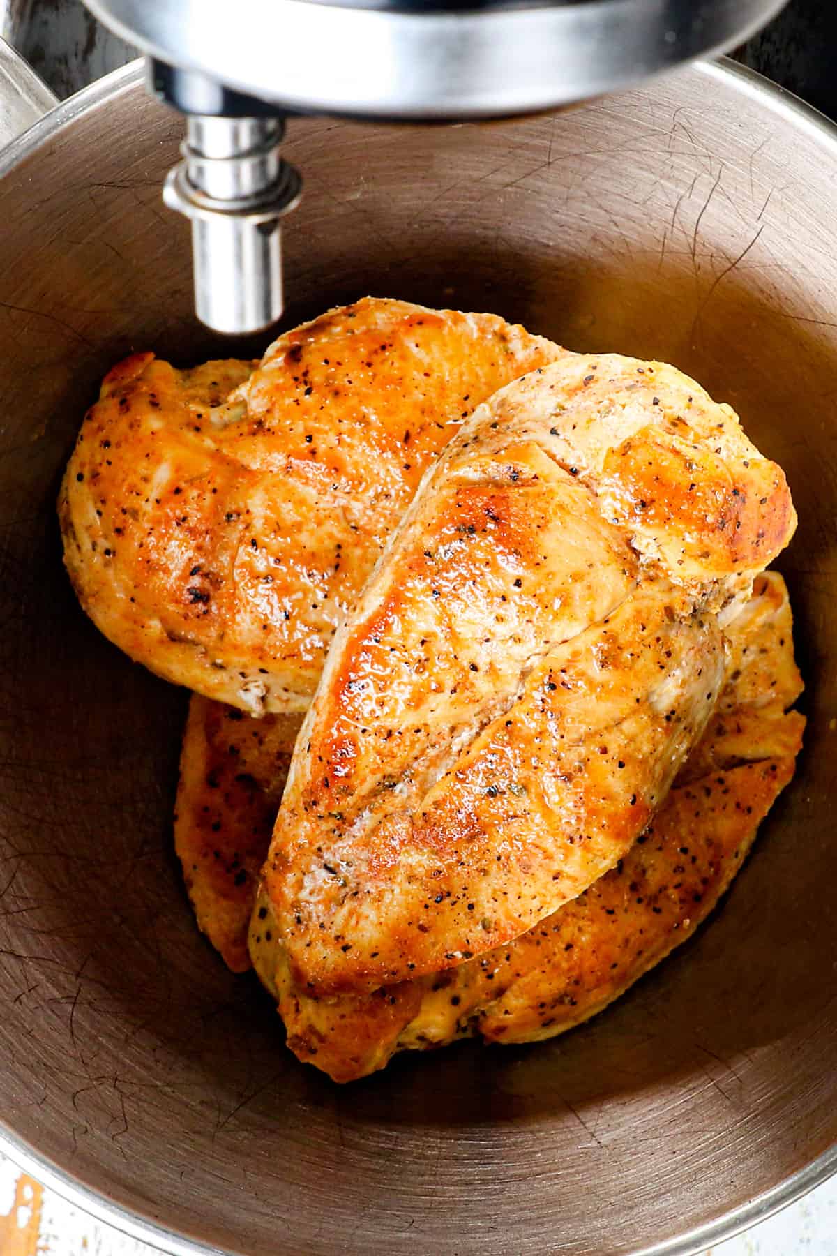 showing how to make shredded chicken by adding it to mixer to shred