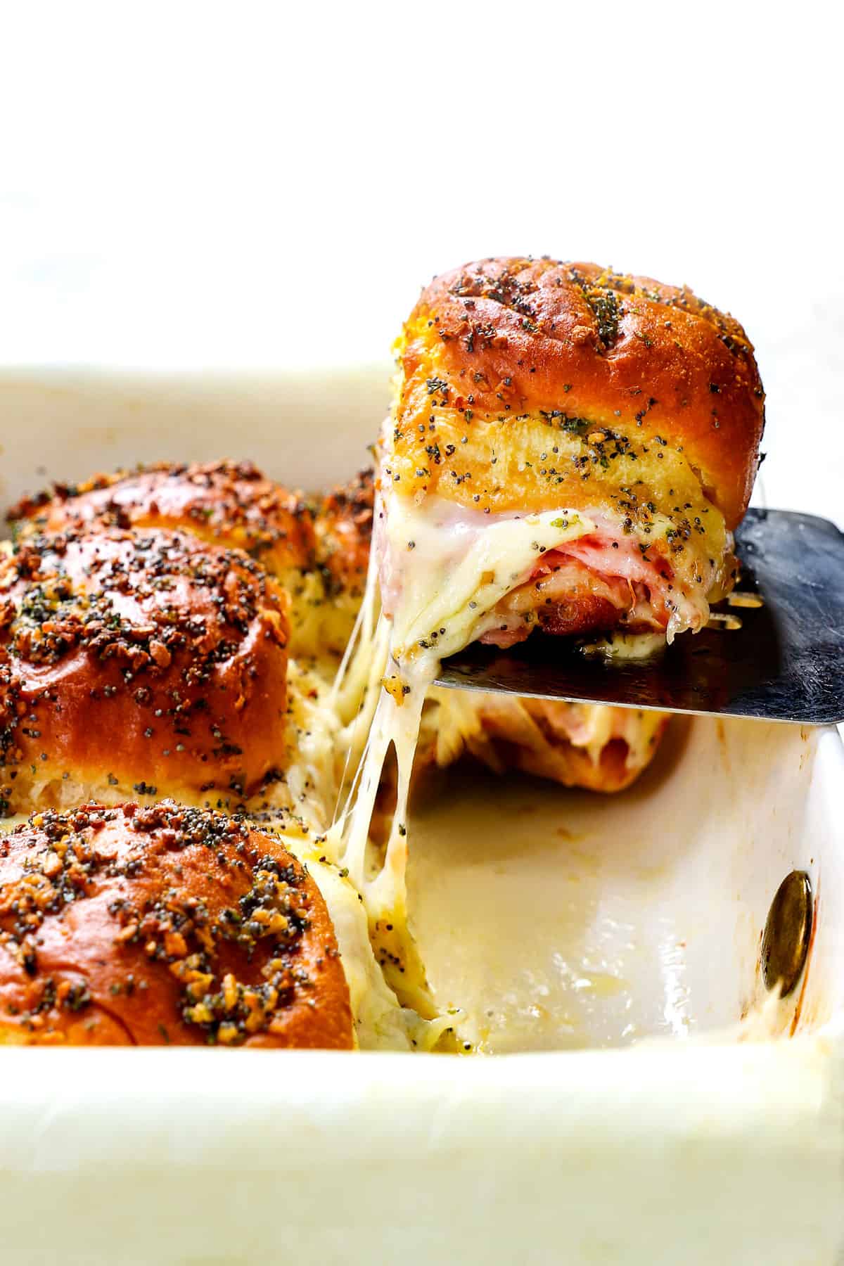 serving Hawaiian ham and cheese sliders with a spatula