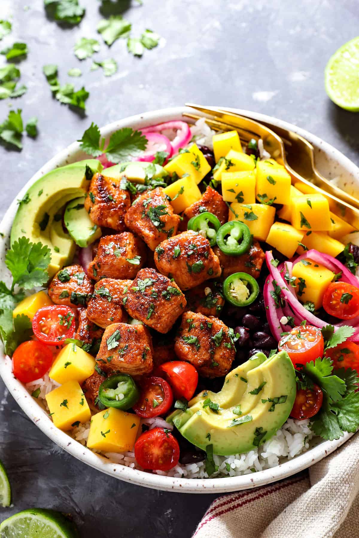 showing how to make chicken bites by adding chicken to a bowl with rice, beans, mangos, avocados
