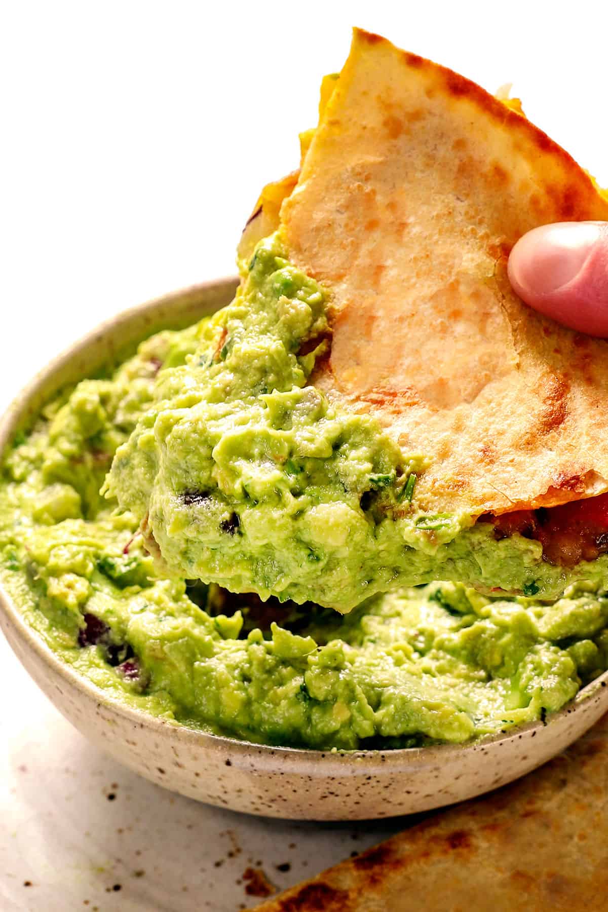showing how to serve chicken quesadilla recipe by dipping quesadilla in guacamole