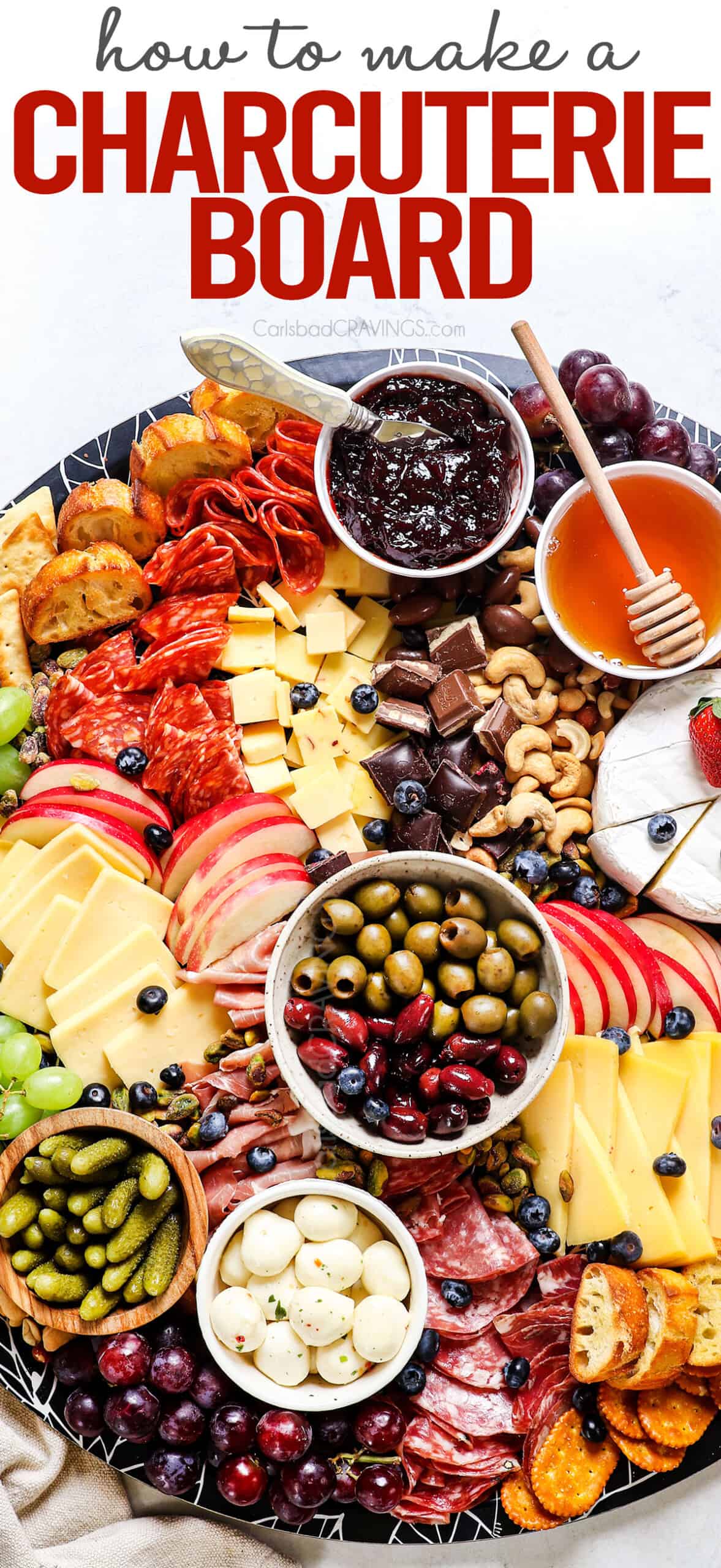 showing how to make a charcuterie board by adding cheeses, meats, fruit, nuts, pickles, olives and crackers to the board