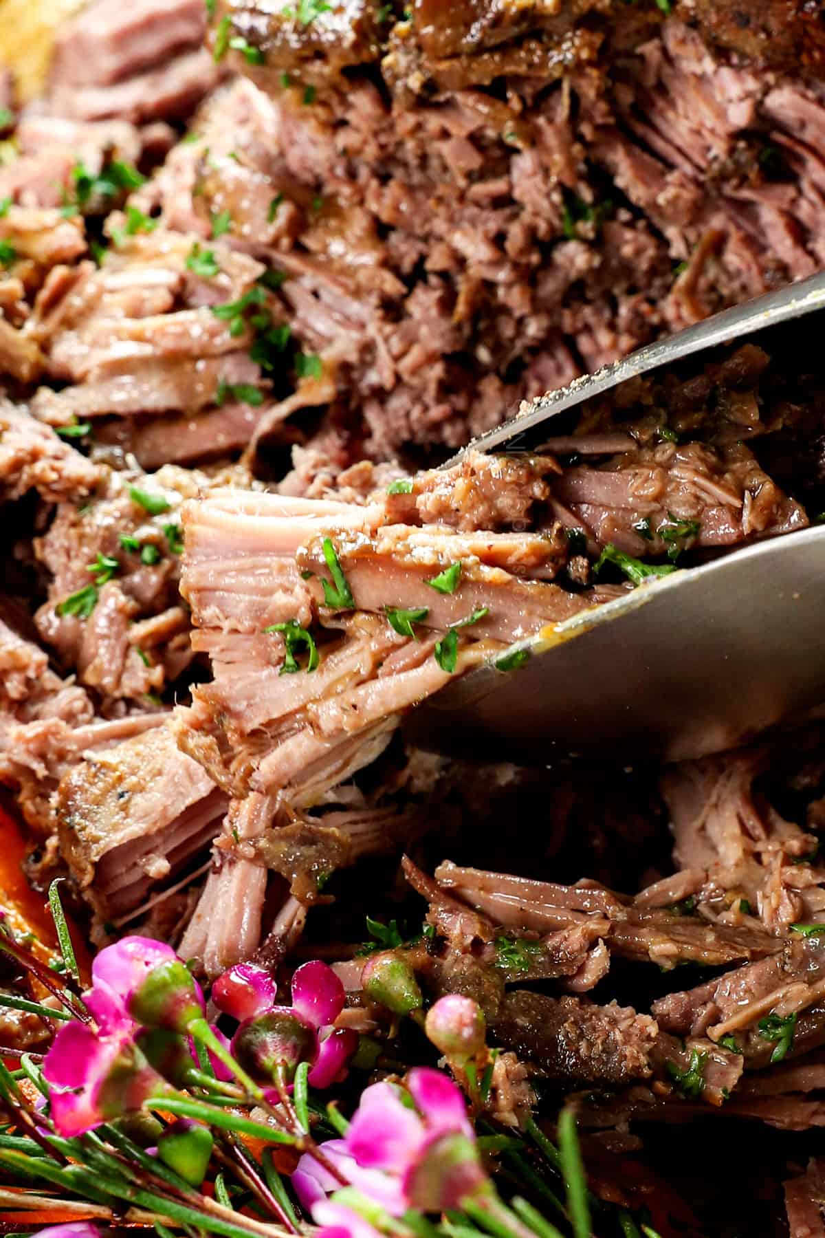 up close of serving roasted leg of lamb with tongs