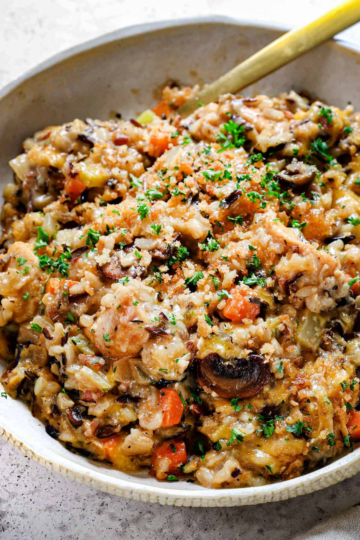 showing how to serve chicken and wild rice casserole in a bowl garnished with fresh parsley