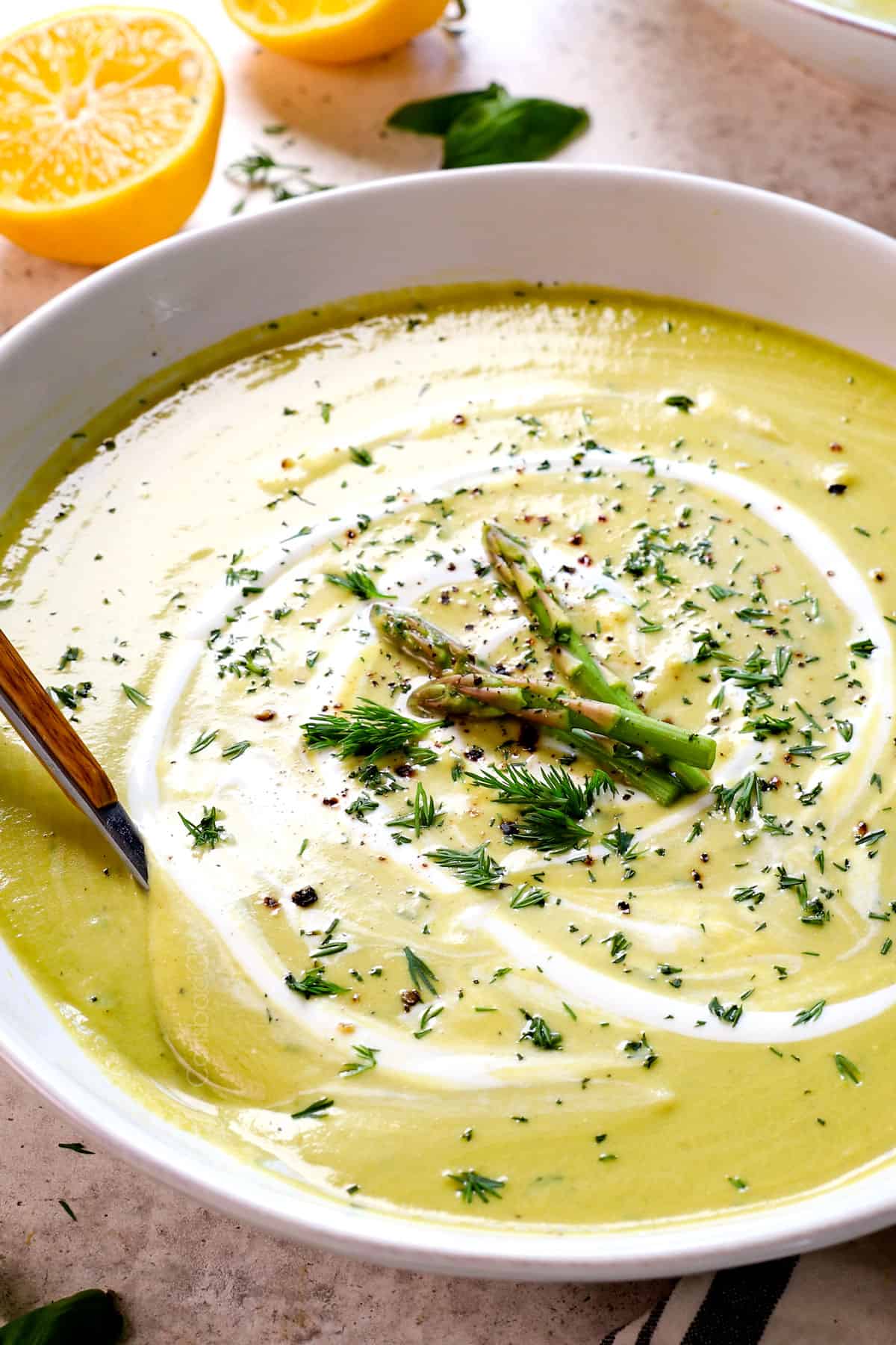 serving a bowl of Creamy Asparagus Soup in bowl garnished with freshly grated Parmesan and Greek yogurt